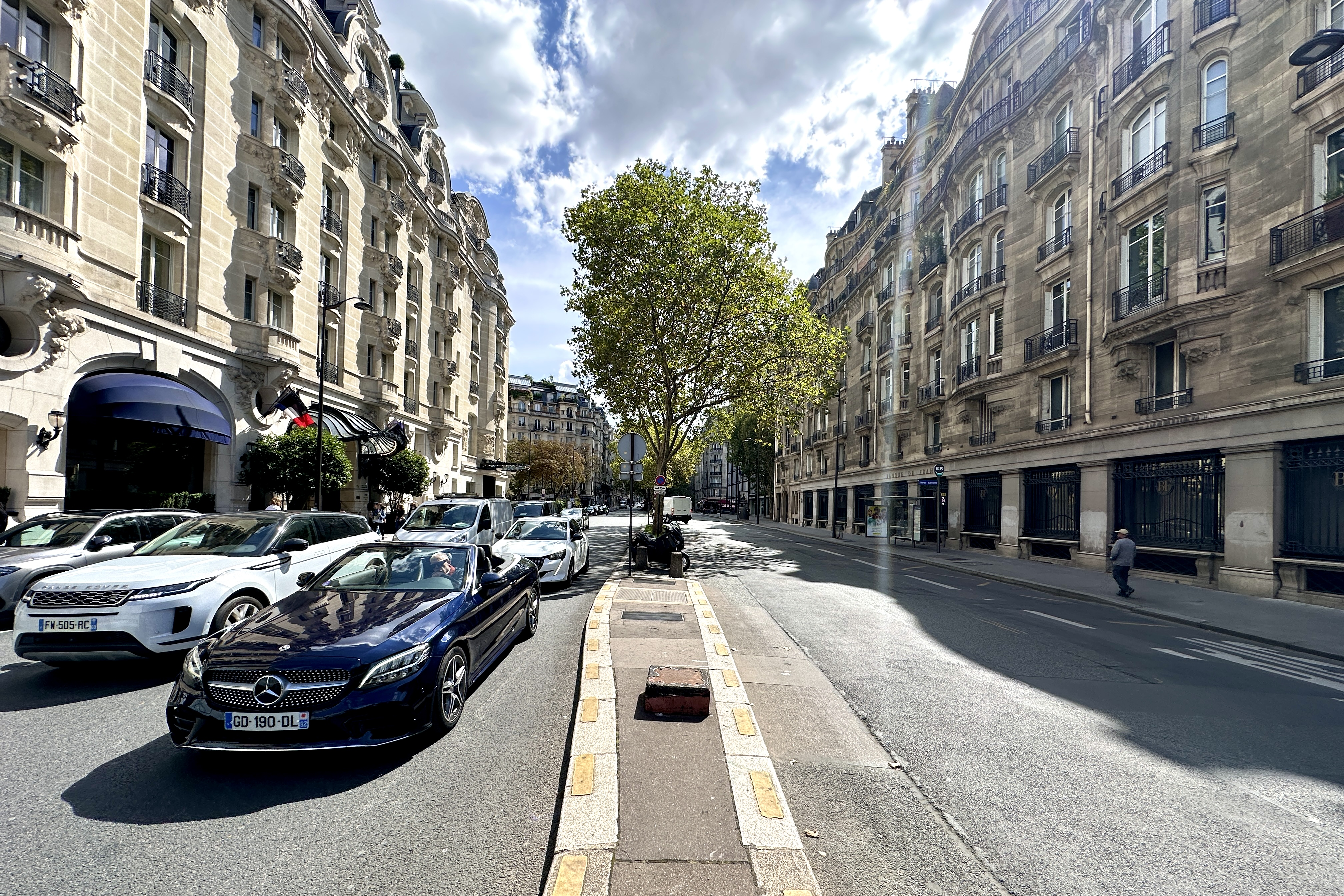 Circulation élégante sur le boulevard Raspail, avec une Mercedes bleue évoquant le raffinement du 6e arrondissement parisien